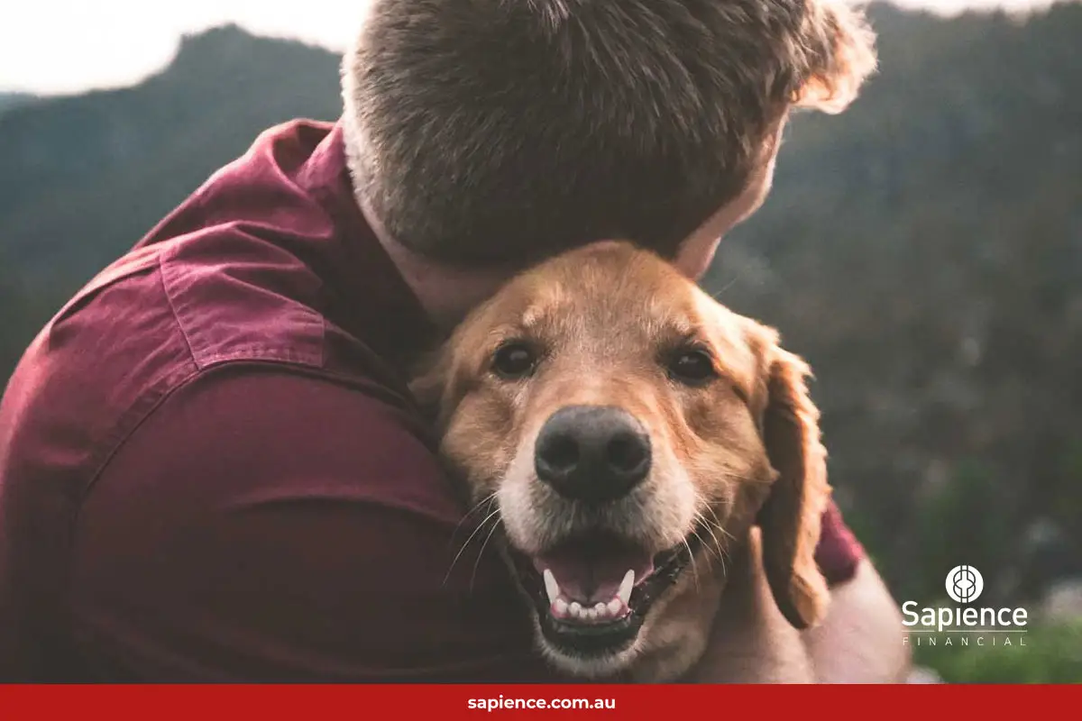 man hugging his dog outside in the mountains